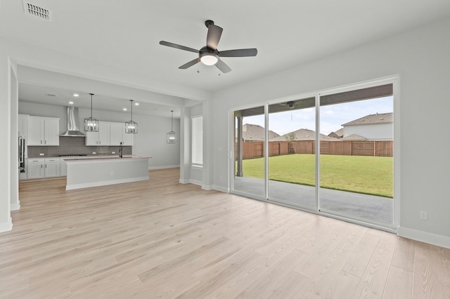 unfurnished living room featuring ceiling fan, light hardwood / wood-style flooring, and a healthy amount of sunlight