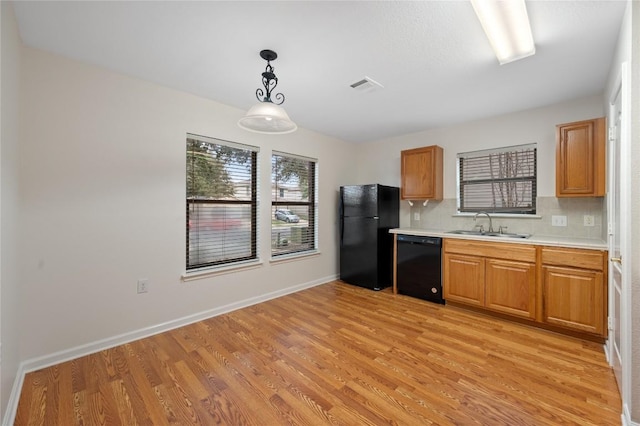 kitchen with light wood-type flooring, tasteful backsplash, sink, black appliances, and hanging light fixtures