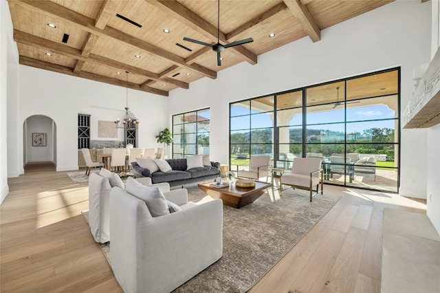 living room featuring beam ceiling, ceiling fan with notable chandelier, a wealth of natural light, and wooden ceiling