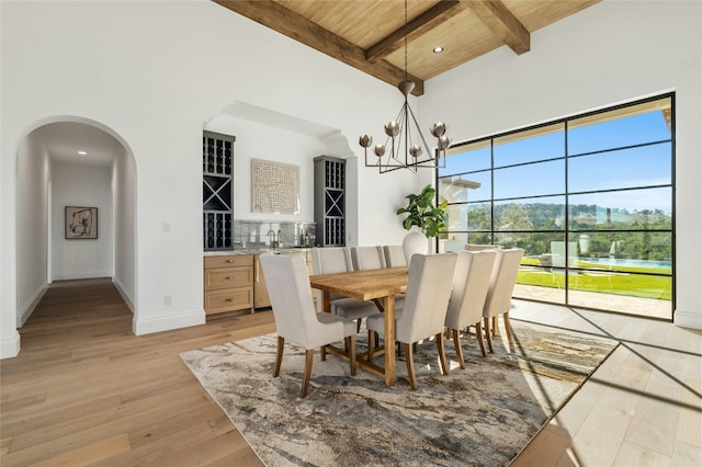 dining room with an inviting chandelier, beamed ceiling, wooden ceiling, and light wood-type flooring