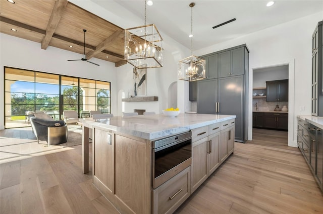 kitchen featuring ceiling fan, light stone counters, beamed ceiling, a spacious island, and wood ceiling