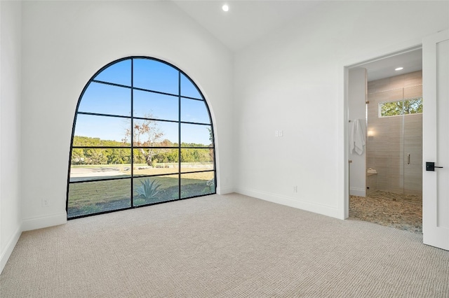 unfurnished living room featuring light colored carpet and high vaulted ceiling