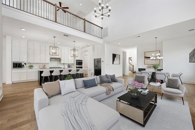 7501 Becasseau Dr, Austin, TX 78738 - living room with a chandelier, light wood-style floors, stairway, a high ceiling, and recessed lighting