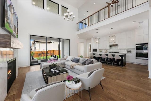 7501 Becasseau Dr, Austin, TX 78738 - living room with a tiled fireplace, wood finished floors, a chandelier, and a towering ceiling