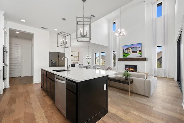 7501 Becasseau Dr, Austin, TX 78738 - kitchen with stainless steel appliances, a chandelier, light countertops, light wood-style floors, and a high ceiling