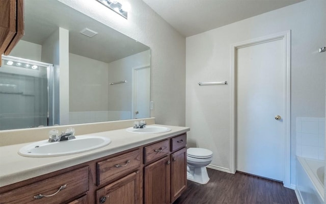 bathroom with a tub to relax in, hardwood / wood-style floors, vanity, and toilet