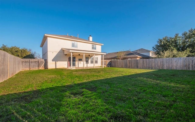 rear view of property with ceiling fan, a yard, and a patio