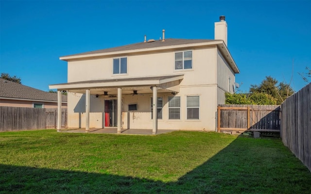 rear view of house featuring ceiling fan, a patio area, and a lawn