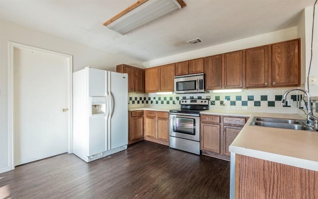 kitchen with decorative backsplash, dark hardwood / wood-style flooring, sink, and appliances with stainless steel finishes