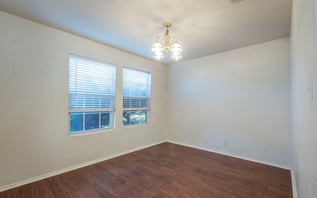 spare room featuring dark hardwood / wood-style floors and a chandelier