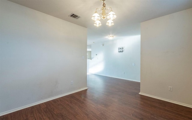 unfurnished room featuring dark hardwood / wood-style floors and a chandelier