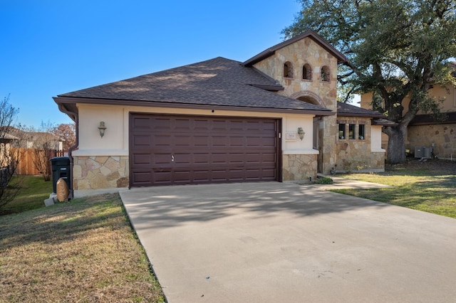 view of front of house featuring a garage, a front lawn, and central air condition unit