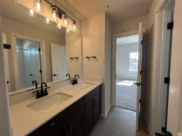 bathroom with double vanity, tile patterned flooring, baseboards, and a sink