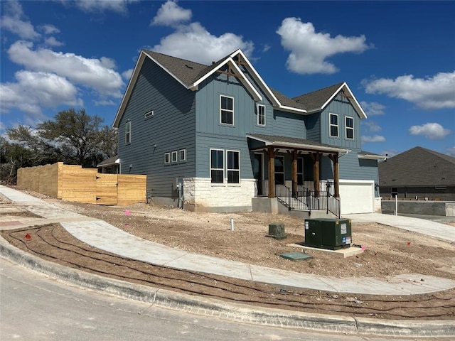 view of front of house with a porch, an attached garage, concrete driveway, stone siding, and board and batten siding