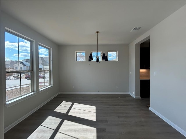 unfurnished dining area with dark wood-type flooring, a wealth of natural light, visible vents, and baseboards