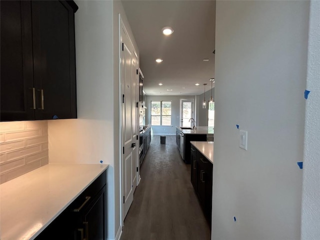 kitchen with dark wood-style flooring, light countertops, dark cabinetry, a sink, and recessed lighting