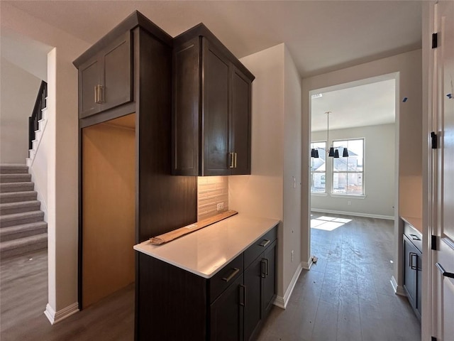 kitchen featuring dark brown cabinets, baseboards, light countertops, and wood finished floors