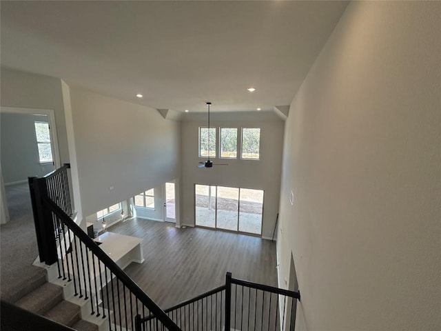 stairs featuring a wealth of natural light, wood finished floors, a towering ceiling, and recessed lighting