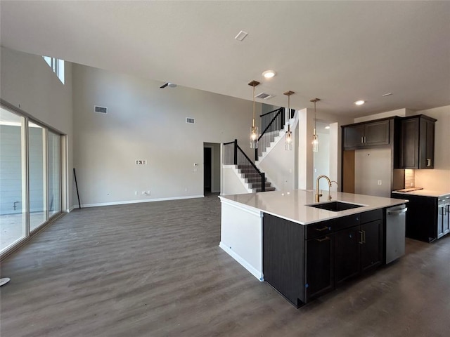 kitchen featuring baseboards, visible vents, open floor plan, light countertops, and a sink