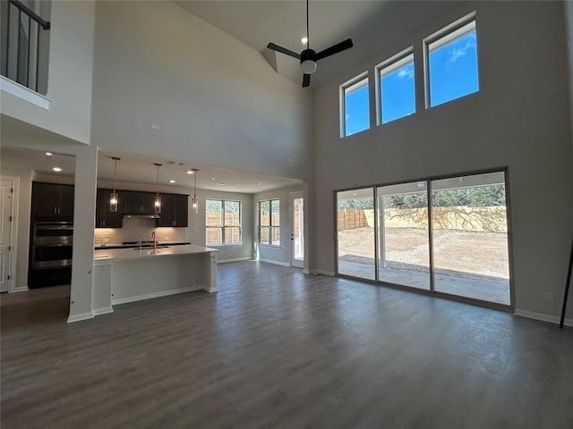 unfurnished living room featuring ceiling fan, recessed lighting, a sink, baseboards, and dark wood-style floors