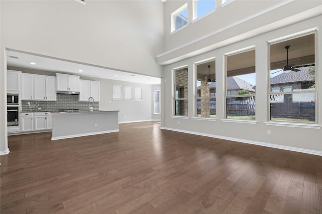 unfurnished living room with ceiling fan, plenty of natural light, dark hardwood / wood-style floors, and sink