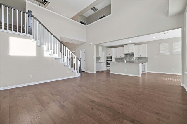 unfurnished living room featuring dark wood-type flooring and a high ceiling