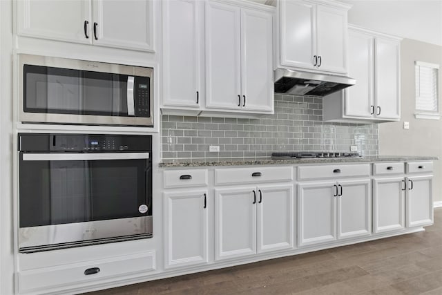 kitchen with stone countertops, light hardwood / wood-style floors, white cabinetry, and appliances with stainless steel finishes