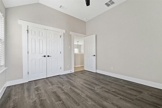 unfurnished bedroom featuring vaulted ceiling, ceiling fan, dark hardwood / wood-style floors, multiple windows, and a closet