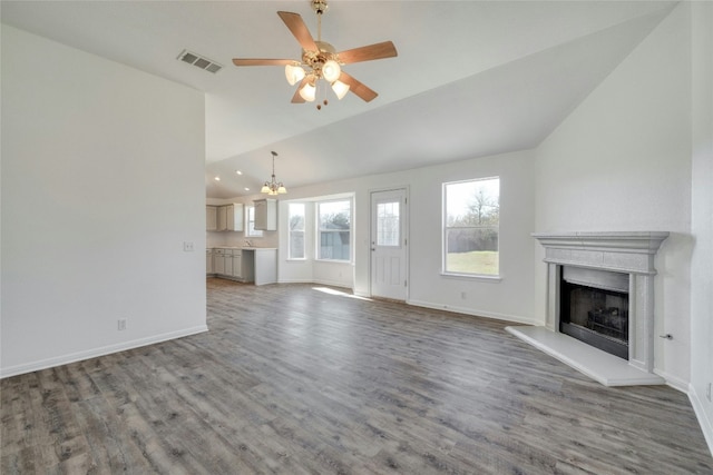 unfurnished living room featuring hardwood / wood-style floors, ceiling fan with notable chandelier, and vaulted ceiling