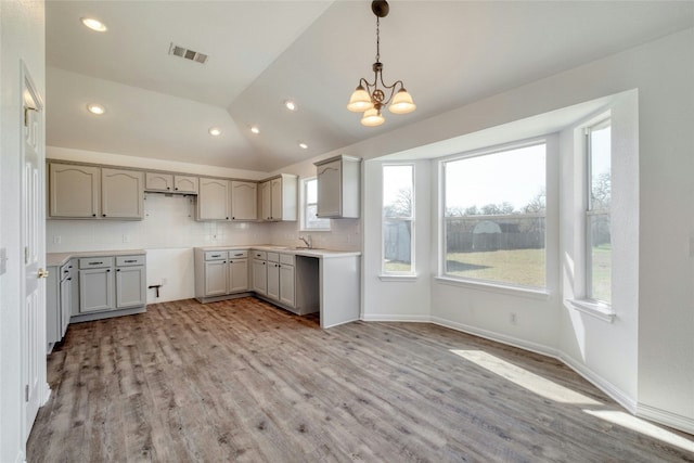 kitchen featuring lofted ceiling, backsplash, an inviting chandelier, gray cabinets, and decorative light fixtures