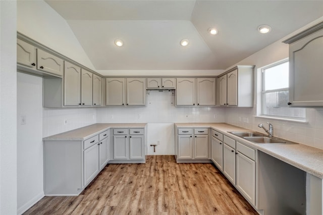 kitchen with gray cabinetry, sink, vaulted ceiling, and light hardwood / wood-style flooring