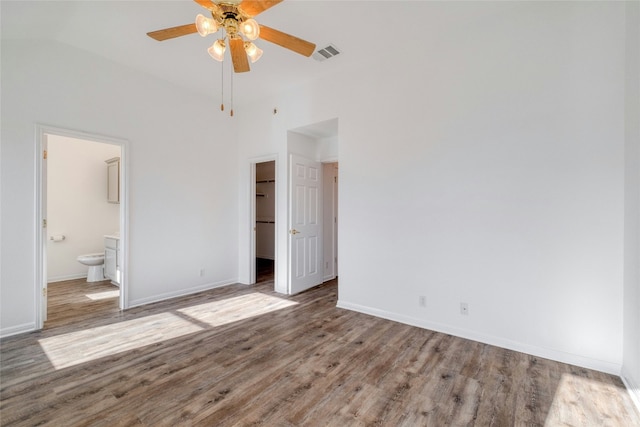 unfurnished bedroom with hardwood / wood-style floors, ensuite bath, ceiling fan, a spacious closet, and a closet