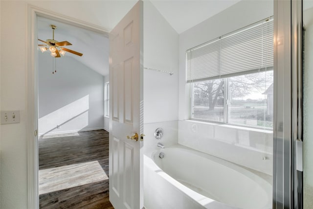 bathroom featuring hardwood / wood-style flooring, vaulted ceiling, ceiling fan, and a tub