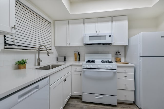 kitchen featuring white appliances, tasteful backsplash, white cabinetry, and sink