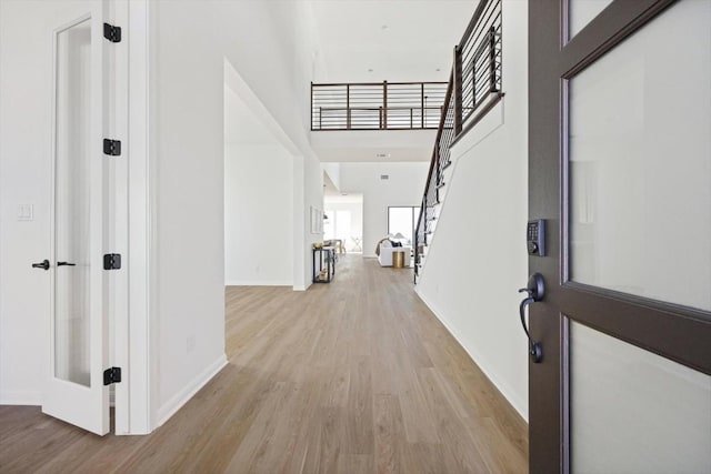 interior space with a towering ceiling and light hardwood / wood-style floors