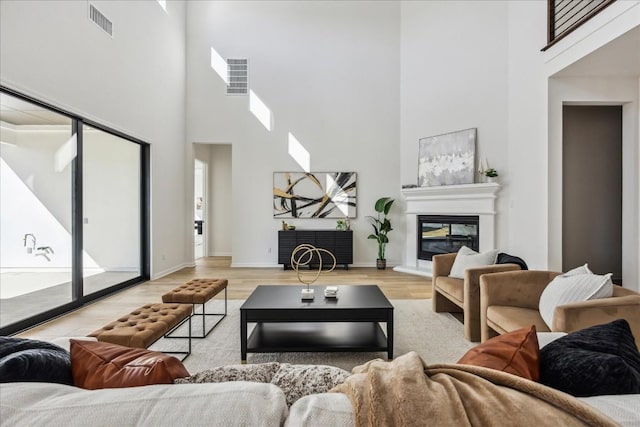 living room with a healthy amount of sunlight, a high ceiling, and light hardwood / wood-style floors