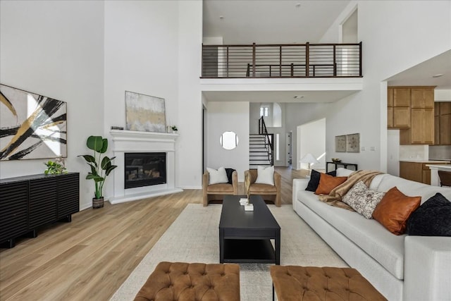 living room with a towering ceiling and light hardwood / wood-style flooring