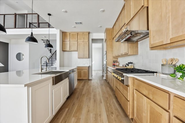 kitchen featuring pendant lighting, sink, light hardwood / wood-style flooring, appliances with stainless steel finishes, and extractor fan