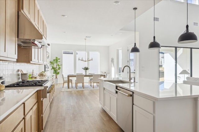 kitchen with sink, a healthy amount of sunlight, stainless steel dishwasher, an island with sink, and pendant lighting