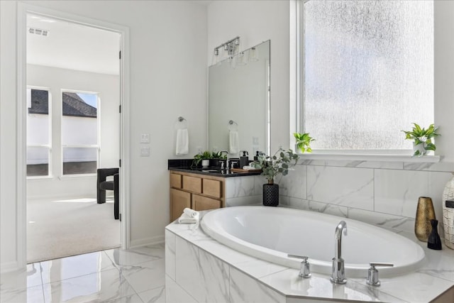 bathroom with vanity and tiled tub