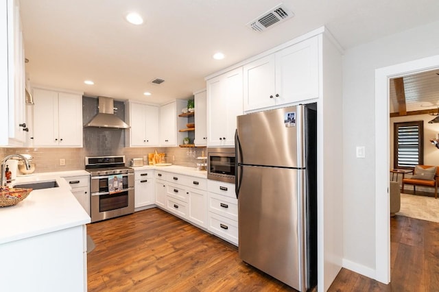 kitchen with appliances with stainless steel finishes, dark hardwood / wood-style flooring, sink, wall chimney range hood, and white cabinetry