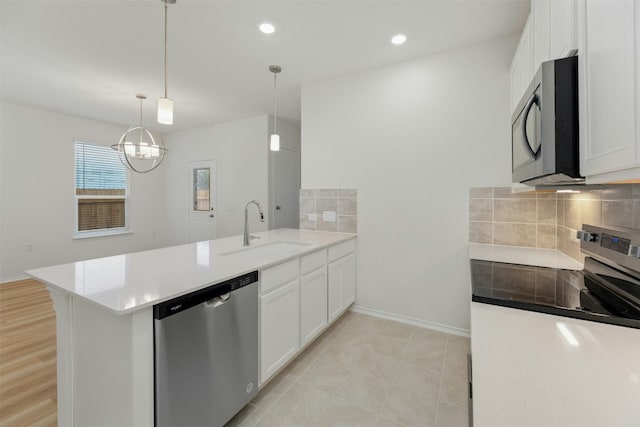 kitchen with sink, stainless steel dishwasher, kitchen peninsula, white cabinets, and range