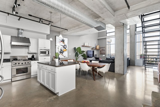 kitchen with wall chimney exhaust hood, stainless steel appliances, pendant lighting, white cabinetry, and a kitchen island