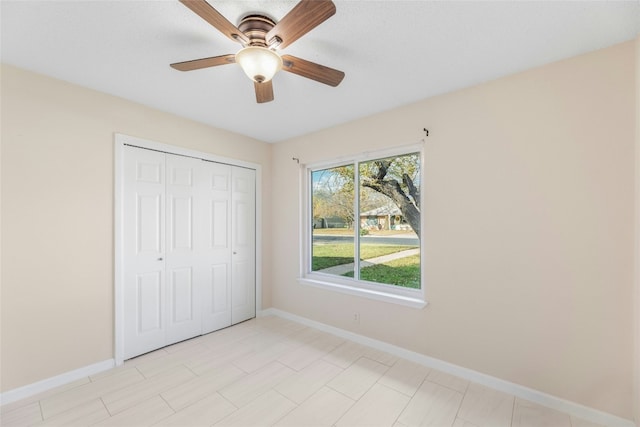 unfurnished bedroom with ceiling fan and a closet