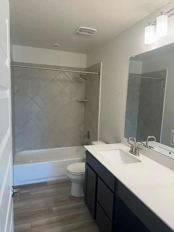 bathroom featuring bathtub / shower combination, toilet, wood finished floors, visible vents, and vanity