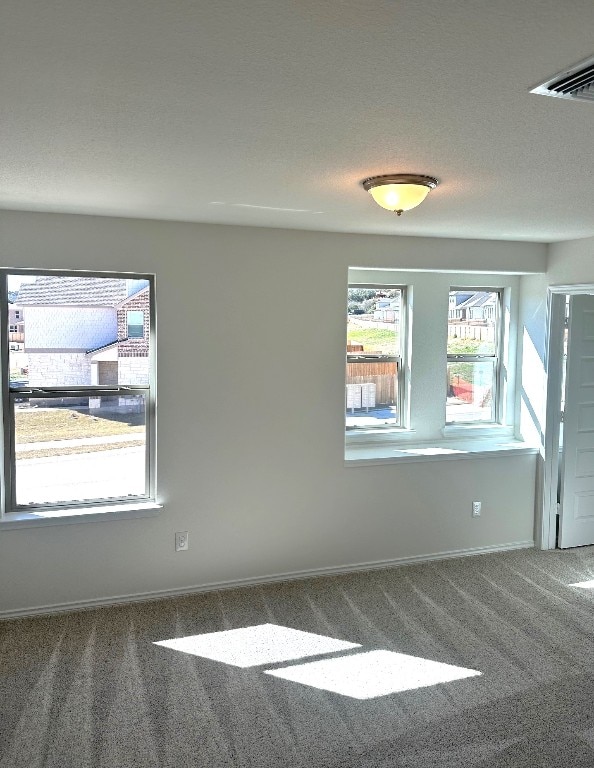 carpeted spare room featuring baseboards and visible vents