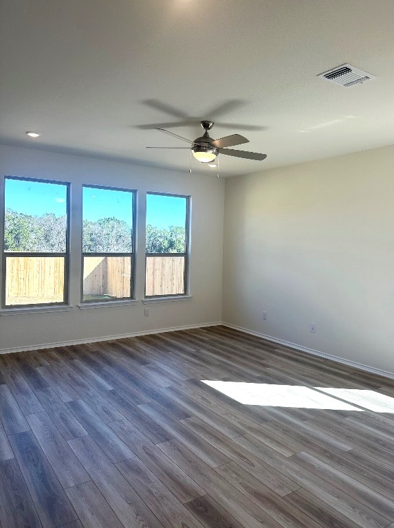 unfurnished room featuring ceiling fan, dark wood-style flooring, visible vents, and baseboards