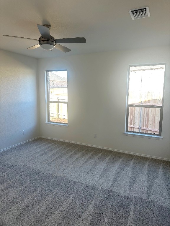 spare room featuring baseboards, carpet floors, visible vents, and a ceiling fan