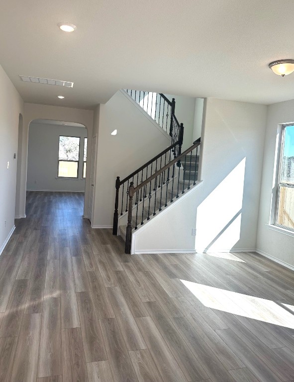 interior space featuring baseboards, plenty of natural light, arched walkways, and wood finished floors