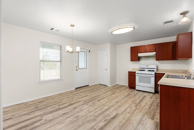 kitchen with white gas stove, sink, a chandelier, decorative light fixtures, and light wood-type flooring